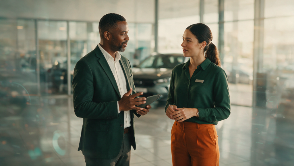 A dealership sales manager and salesperson in conversation on a South African car showroom floor